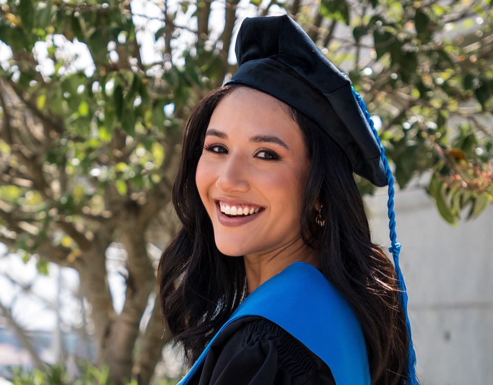 Graduada sonriendo con birrete, toga y estola azul