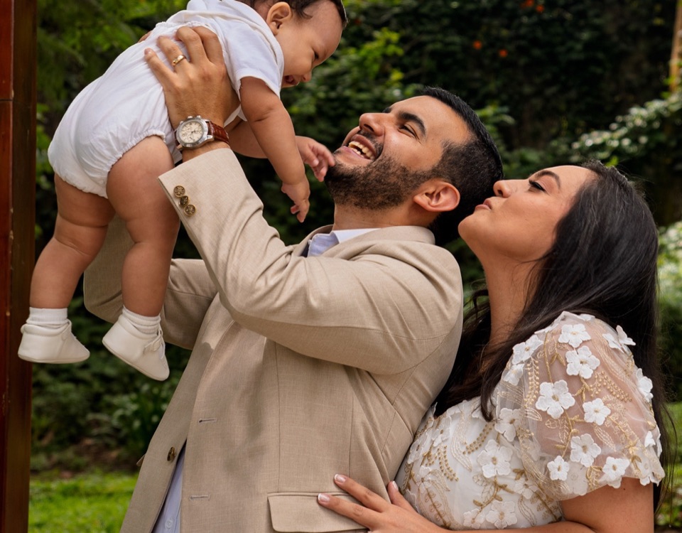 Padre levantando a su bebé en brazos mientras la madre sonríe