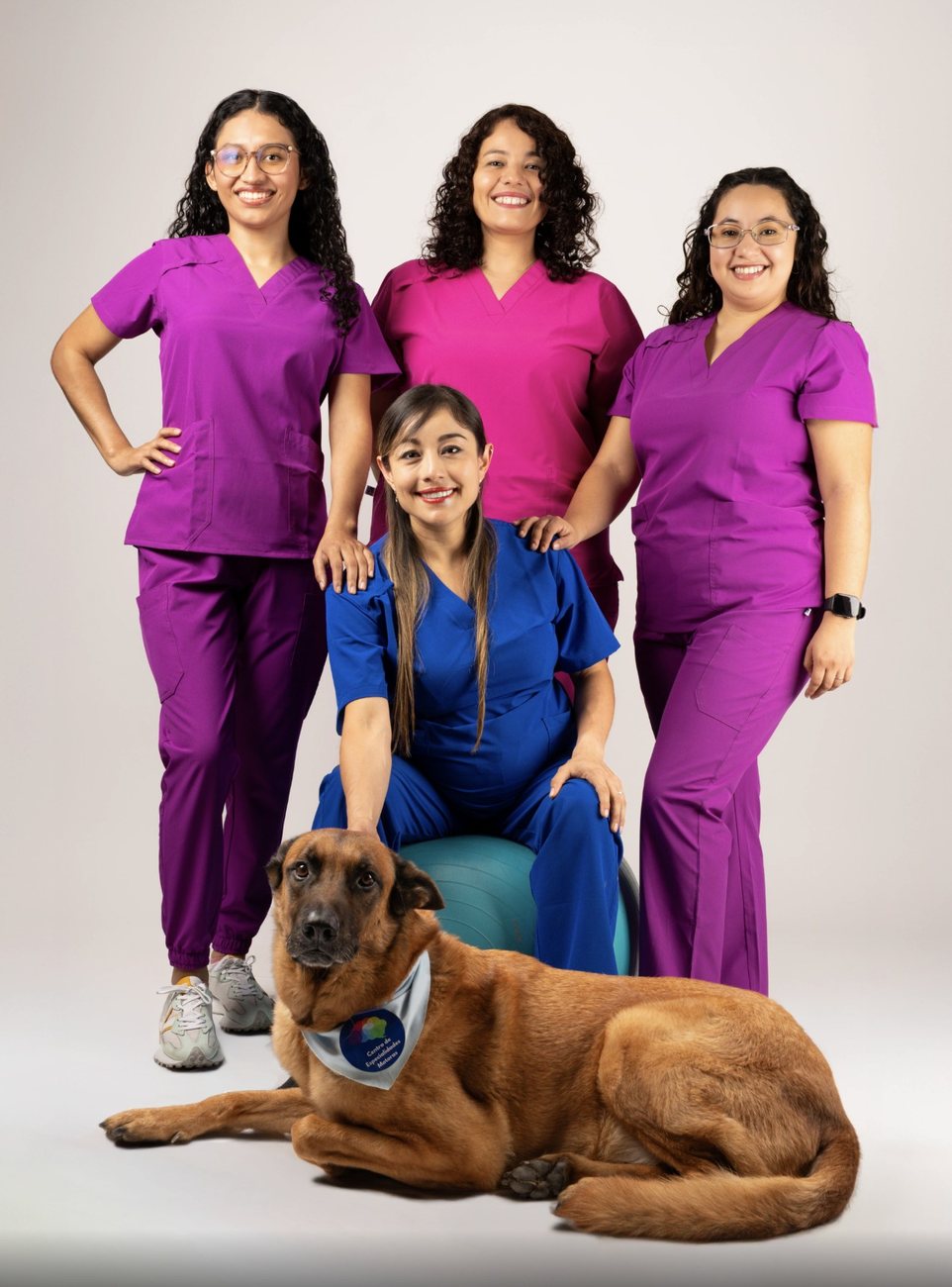Equipo de fisioterapeutas con uniformes de colores y su perro en el estudio