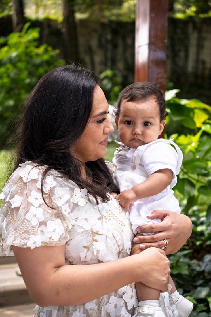 Madre sonriendo con su bebé en brazos durante un bautizo