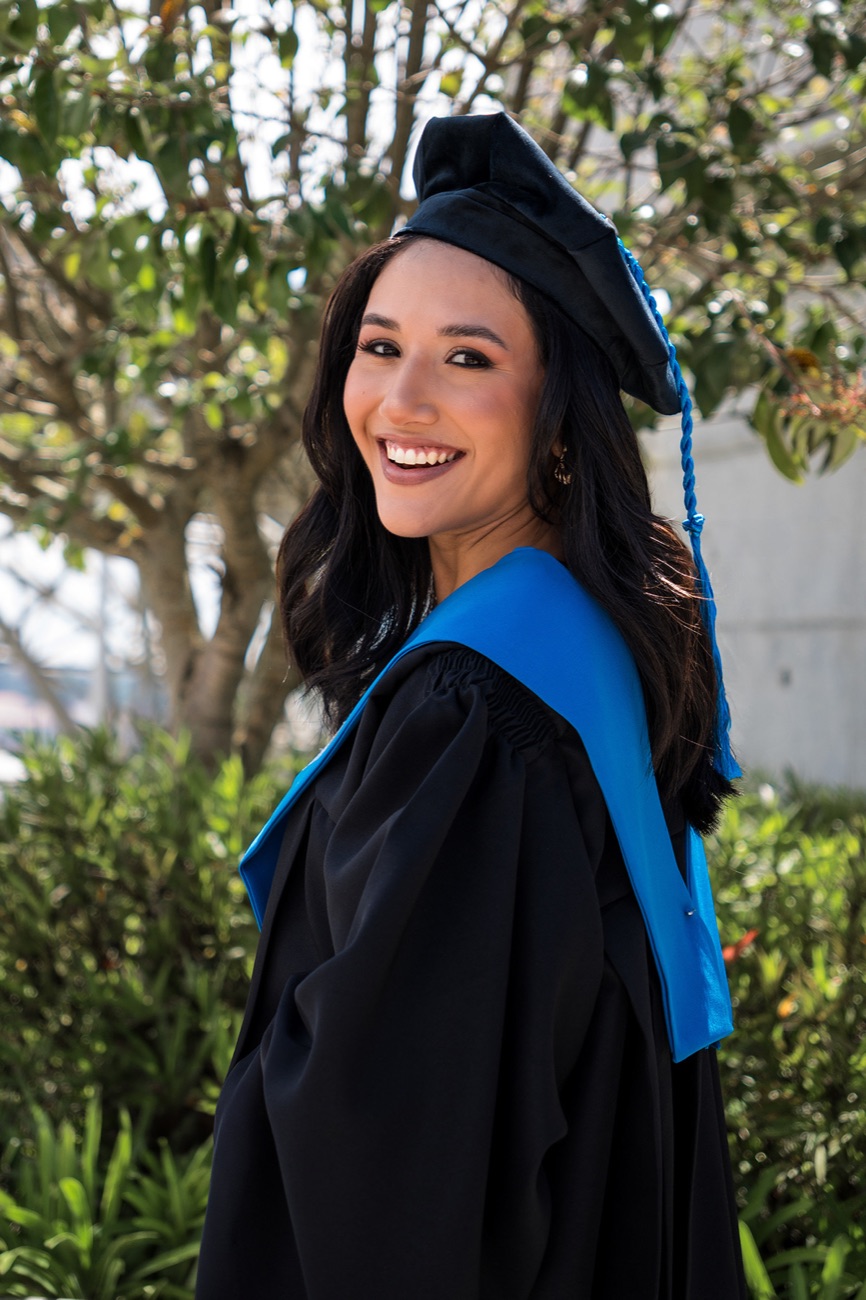 Graduada sonriendo con birrete, toga y estola azul